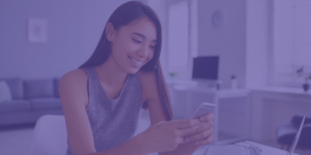 Mulher a sorrir com um telemóvel na mão a navegar nele.