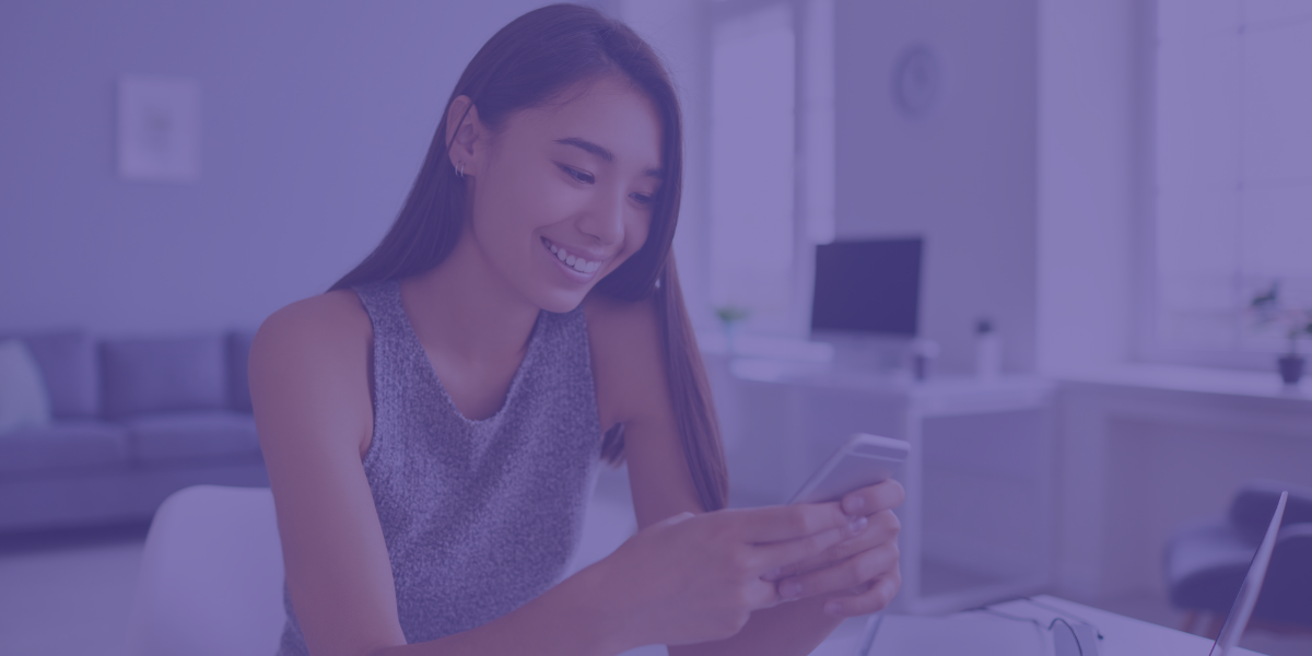 Mulher a sorrir com um telemóvel na mão a navegar nele.
